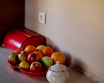 Kitchen counter with a bowl of apples on top in front of a peach colored interior wall.